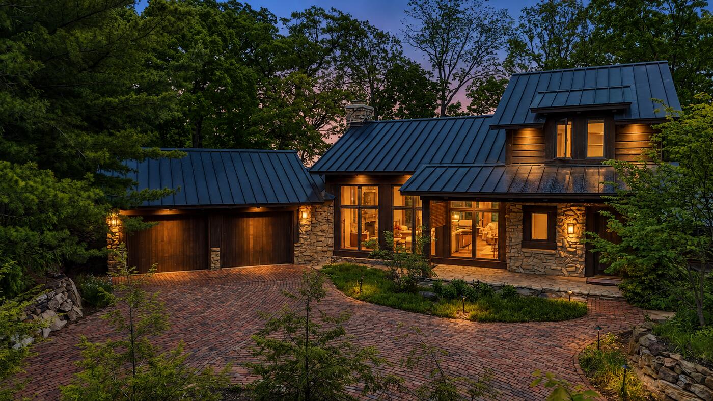 Stone and timber home photographed at twilight with the windows lit